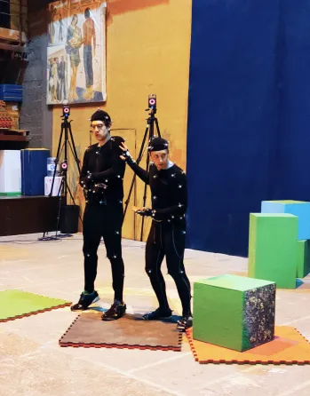 Performers in motion-capture suits recording a scene on a production stage.